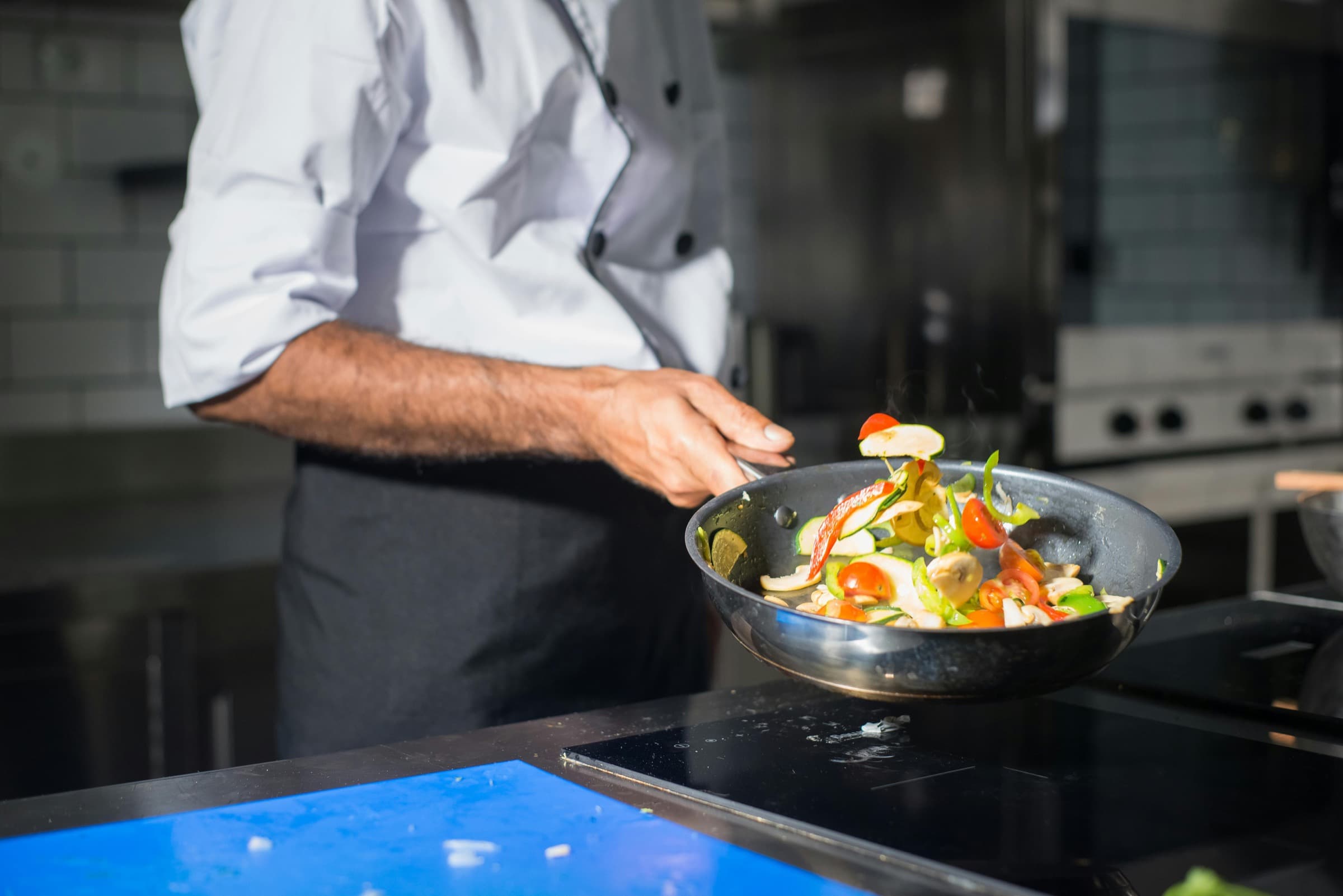 Chef tossing fresh vegetables in a pan during a cooking session