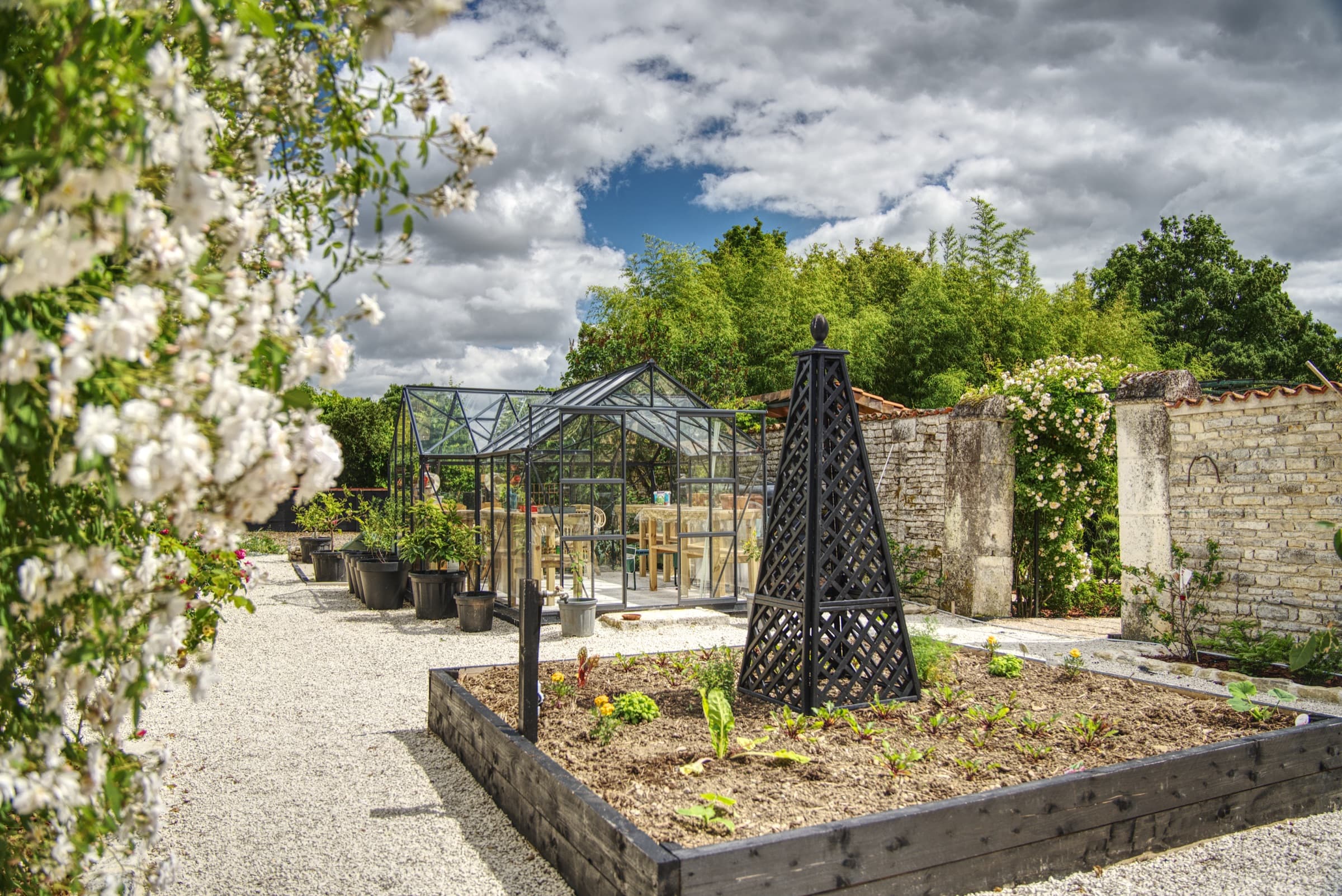 Château Lesvescault — walled kitchen garden with raised beds and greenhouse beyond