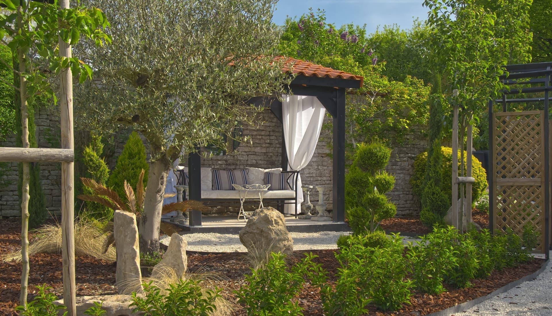 Château Lesvescault — stone wall cabana with daybed and white curtains