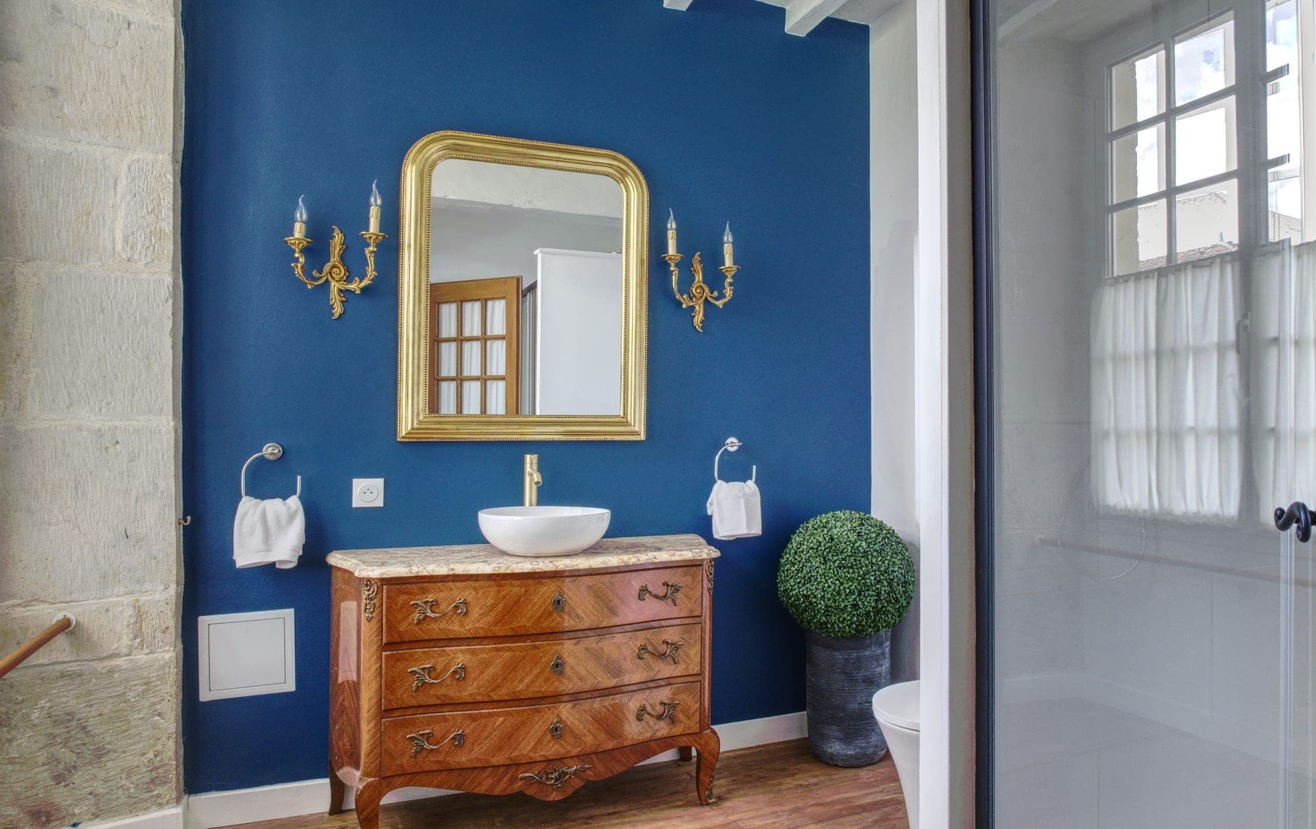 Maison Olivier — cobalt blue bathroom with antique dresser vanity and gilded mirror, Château Lesvescault